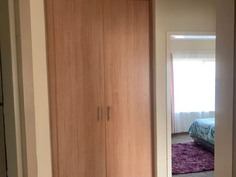 A hallway featuring a built-in wooden wardrobe with modern handles, providing convenient storage space within the apartment.