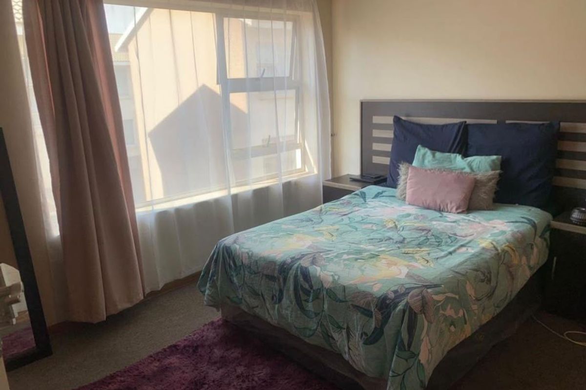A functional bedroom featuring a large window for natural light and a built-in headboard, offering a comfortable and well-lit living space.