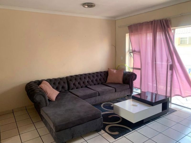 A living room featuring tiled flooring and a sliding glass door providing access to an outdoor area.