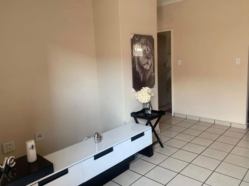 A living area featuring neutral wall tones and tiled flooring, providing a clean and functional space for relaxation.