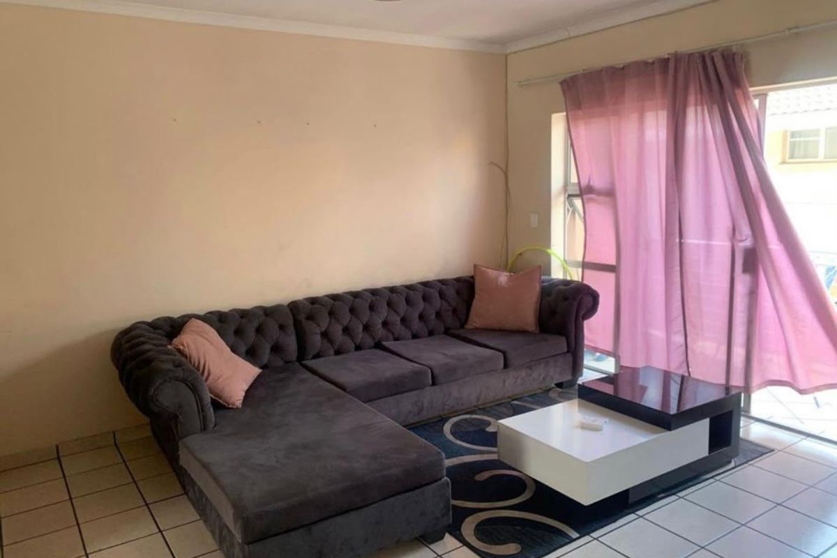 A living room featuring tiled flooring and a sliding glass door providing access to an outdoor area.