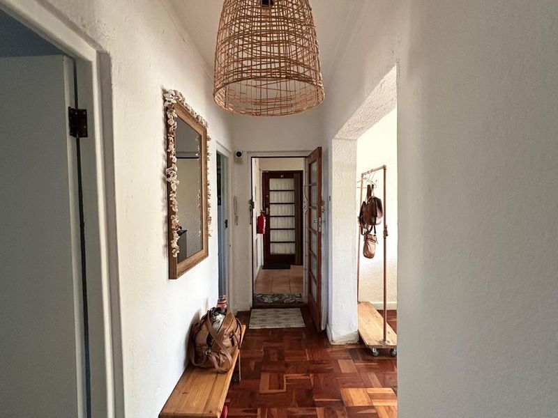 A bright hallway featuring classic parquet flooring and neutral walls, providing access to multiple rooms within the apartment.