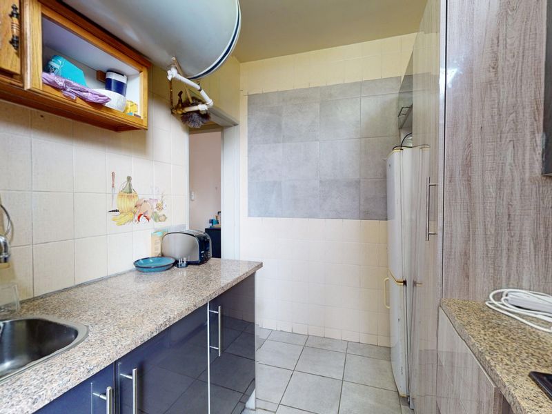 A functional kitchen featuring granite countertops, stainless steel sink, built-in cabinetry, and tiled finishes, offering a practical layout for daily meal preparation.