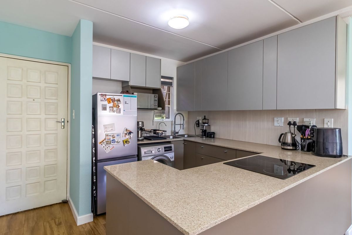 Modern kitchen featuring sleek grey cabinetry, stone countertops, an integrated electric hob, and a functional layout with an undermount sink.