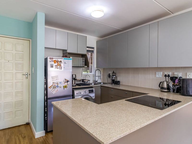 Modern kitchen featuring sleek grey cabinetry, stone countertops, an integrated electric hob, and a functional layout with an undermount sink.