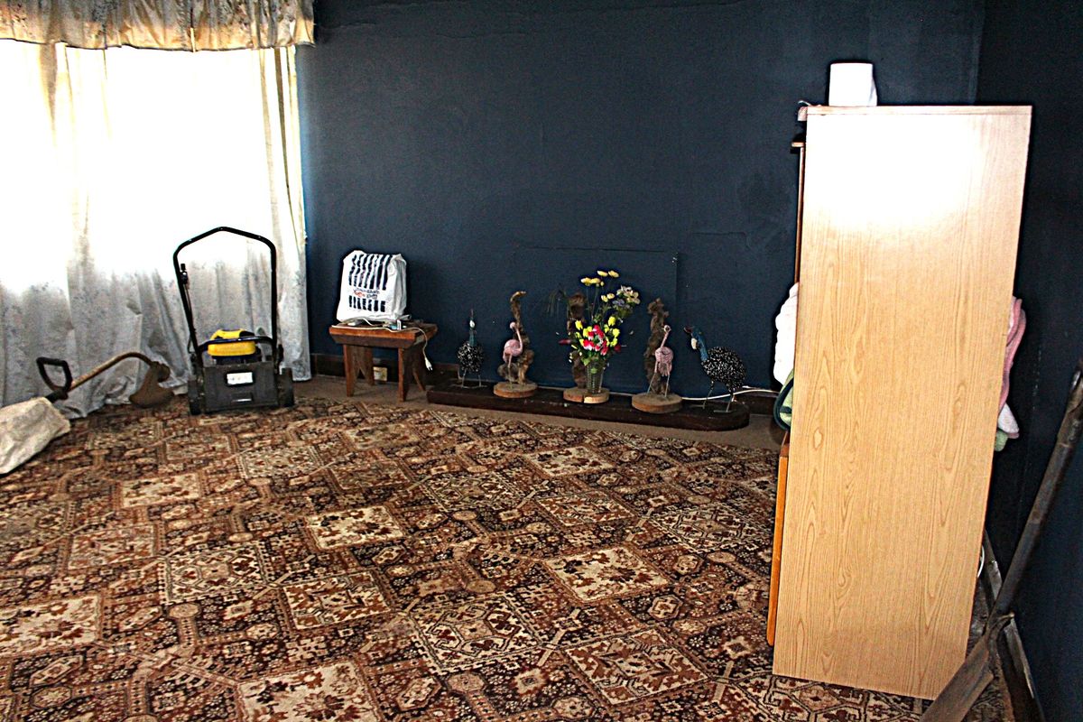 A bedroom featuring dark painted walls and patterned carpeting, requiring cosmetic updates to improve the overall aesthetic and condition of the space.