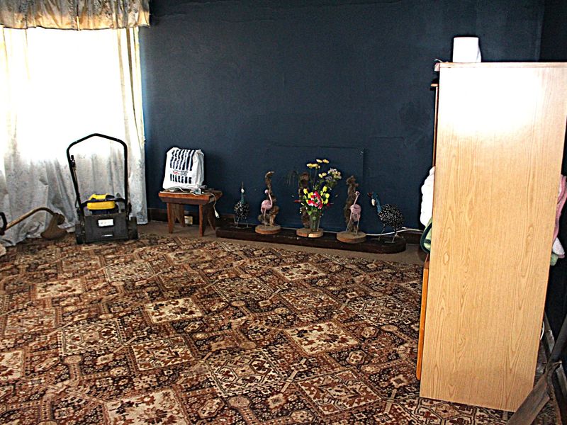 A bedroom featuring dark painted walls and patterned carpeting, requiring cosmetic updates to improve the overall aesthetic and condition of the space.