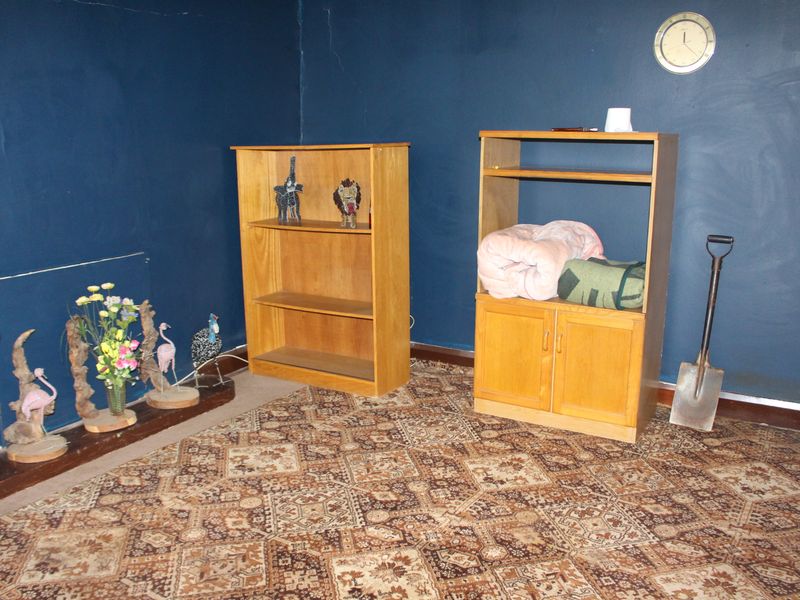 A living room space featuring patterned carpet flooring and dark blue painted walls, currently used for storage.