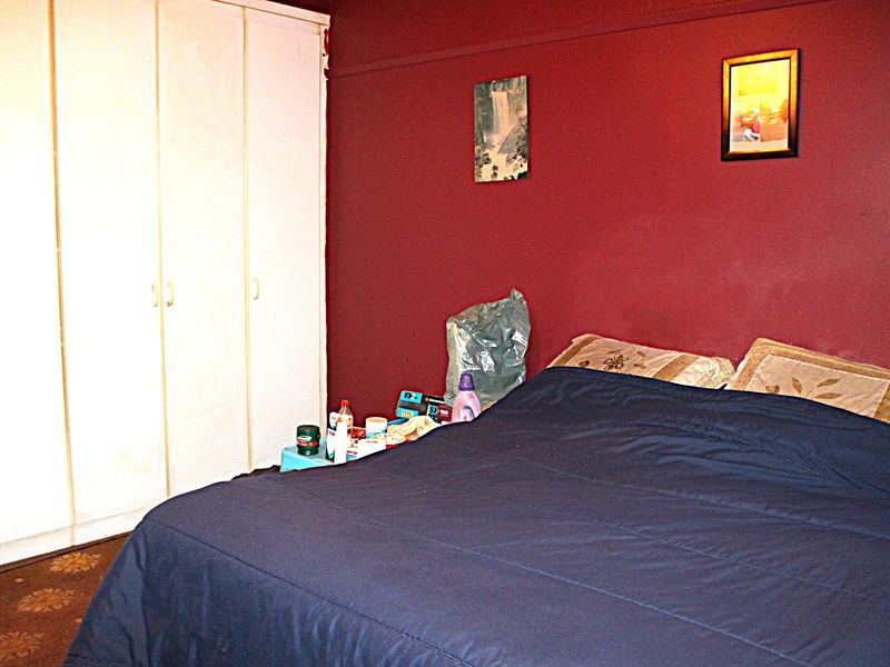 A bedroom featuring built-in cupboards and dark red wall finishes.