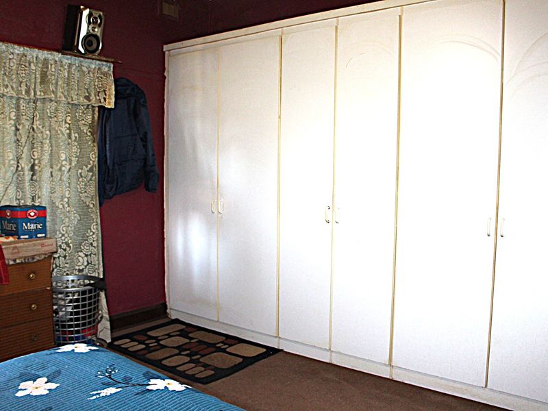 A bedroom featuring a large, white built-in wardrobe with multiple doors, providing ample storage space.