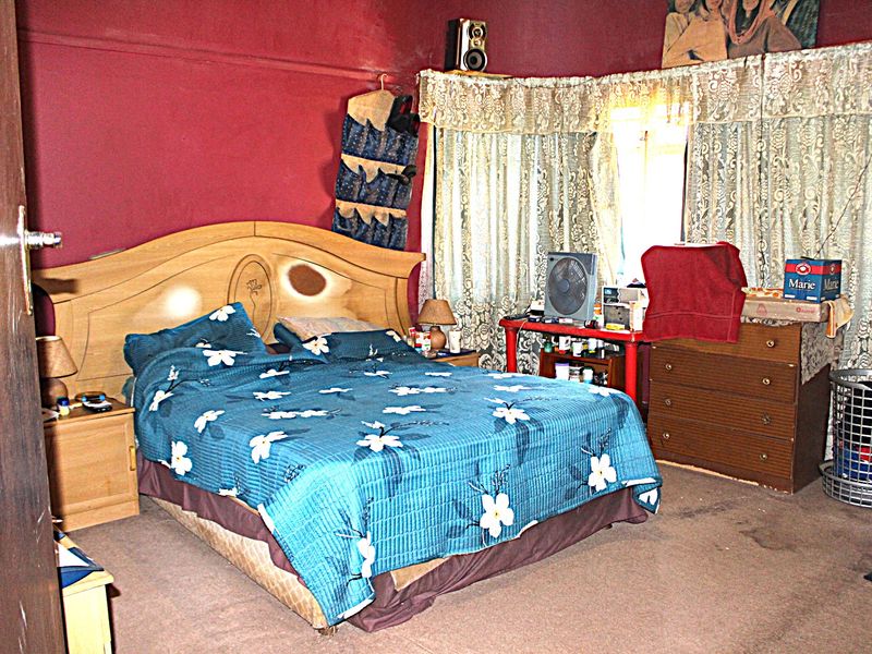 A bedroom featuring red painted walls and carpeted flooring, offering a blank canvas for potential cosmetic updates and interior design improvements.