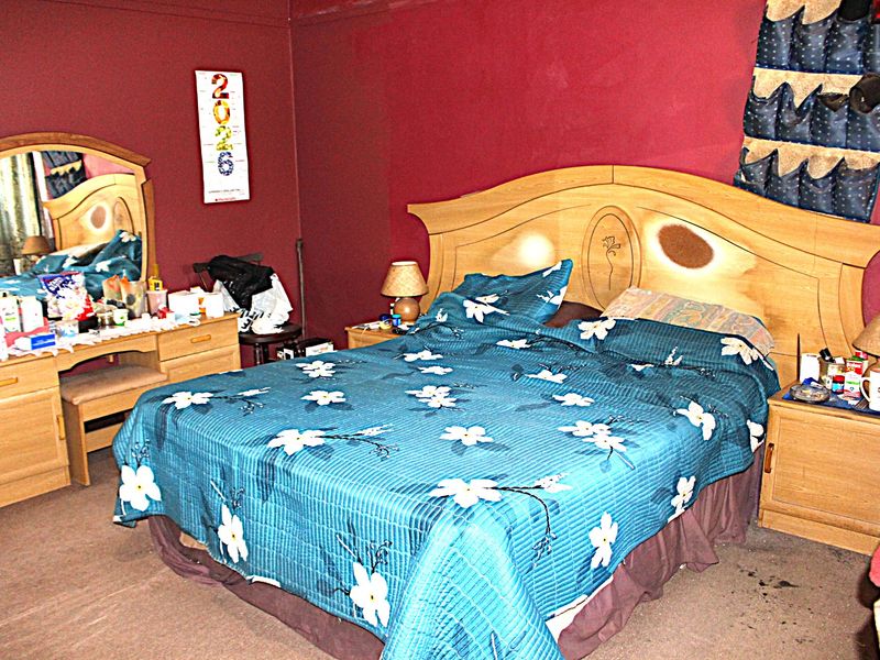 A bedroom featuring dark red walls and carpet flooring, requiring cosmetic updates to improve the overall aesthetic and condition.