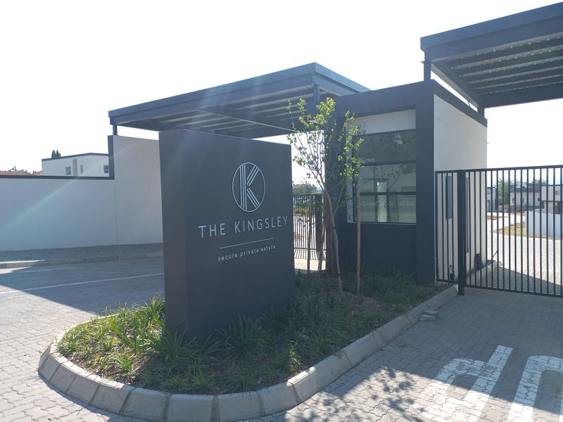 The entrance to The Kingsley secure private estate, featuring modern architectural signage, a paved driveway, and a controlled access gate structure.