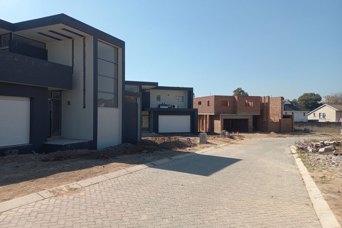 Street view of a residential development featuring modern architectural homes in various stages of completion with paved access roads.