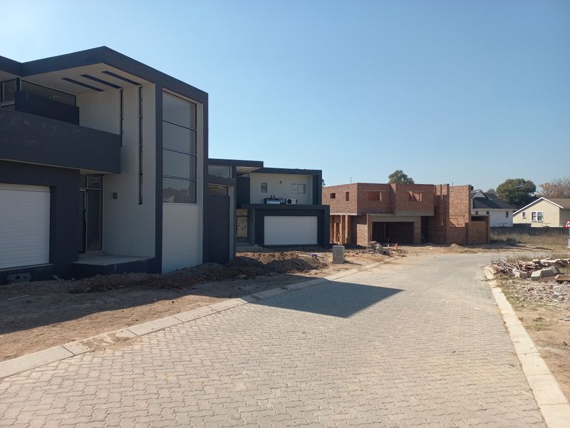 Street view of a residential development featuring modern architectural homes in various stages of completion with paved access roads.