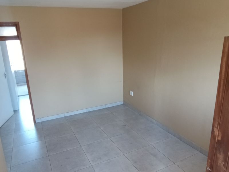 An empty bedroom featuring neutral wall paint and tiled flooring, providing a blank canvas for personalization.