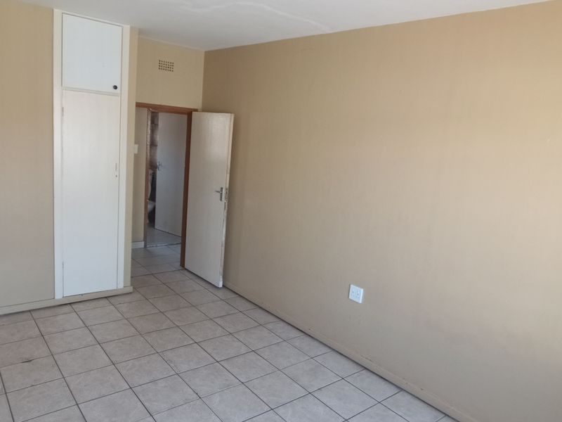 An empty bedroom featuring tiled flooring and a built-in cupboard, offering a blank canvas for renovation or interior design updates.
