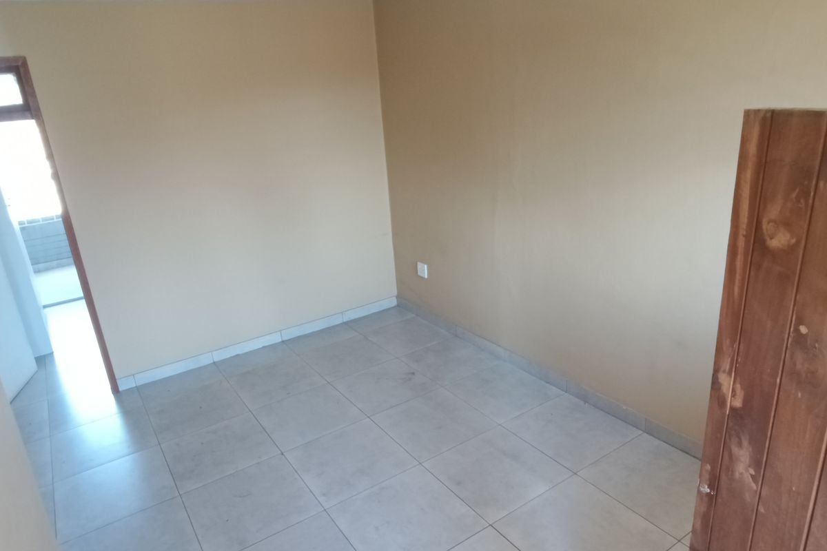 An empty bedroom featuring tiled flooring and neutral wall paint, providing a blank canvas for potential interior design updates.