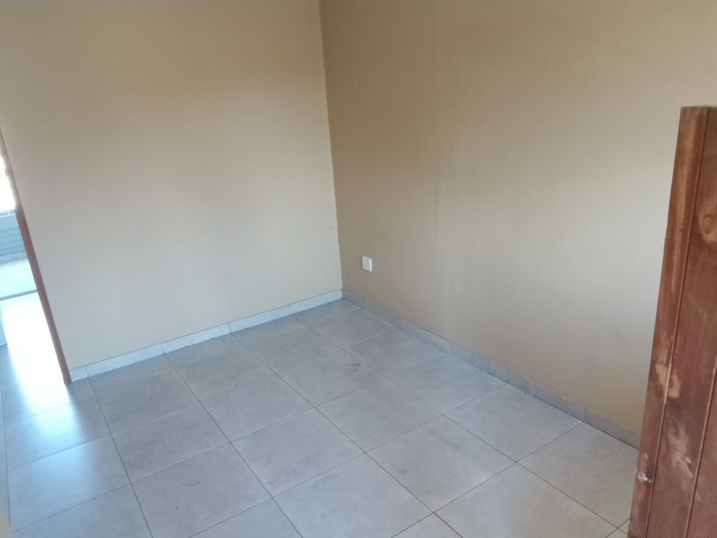 An empty bedroom featuring tiled flooring and neutral wall paint, providing a blank canvas for potential interior design updates.