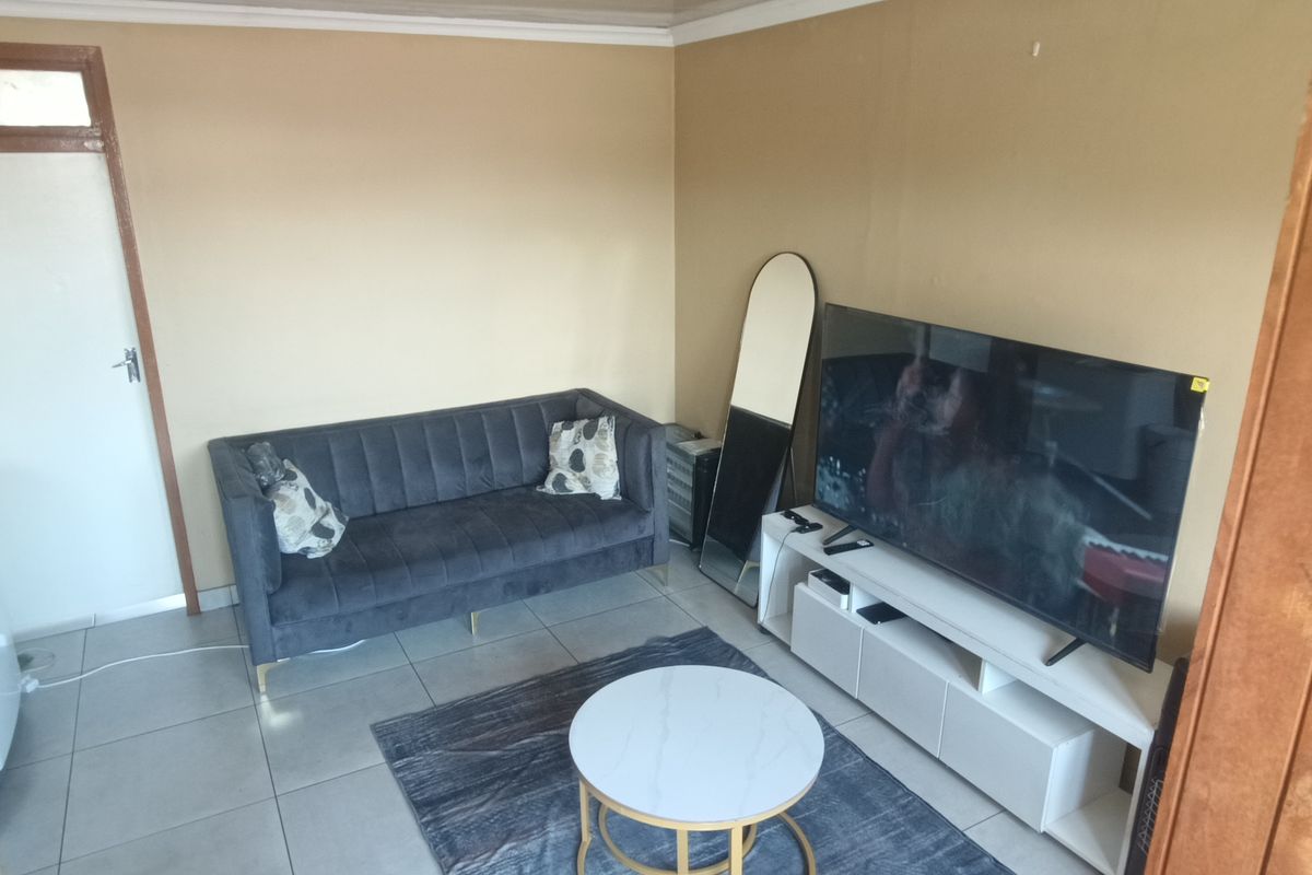 A compact living room featuring tiled flooring and neutral wall finishes, providing a functional space for relaxation.