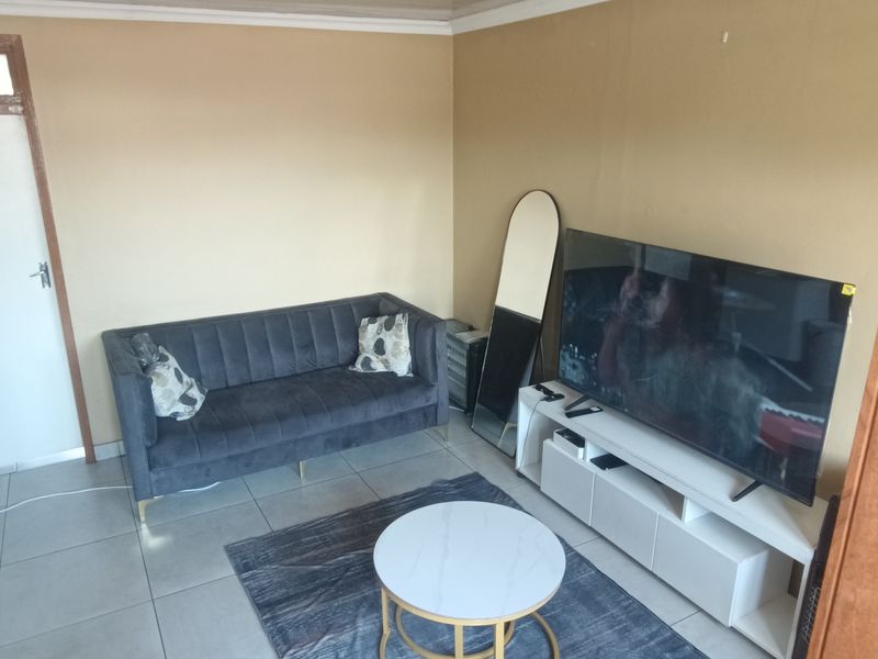 A compact living room featuring tiled flooring and neutral wall finishes, providing a functional space for relaxation.
