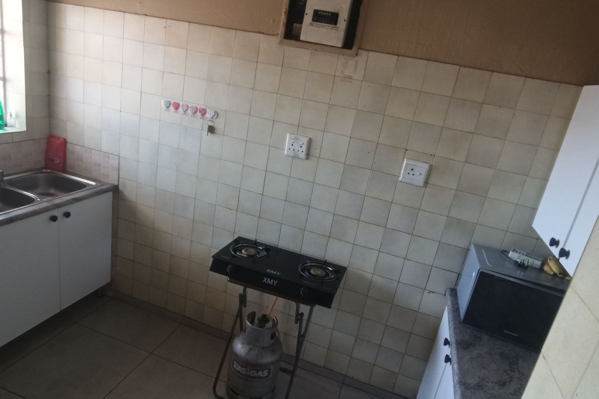 A functional kitchen featuring a double basin sink, tiled splashback, and built-in cabinetry, offering a practical layout for daily meal preparation.