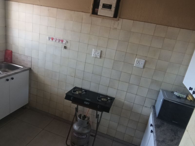 A functional kitchen featuring a double basin sink, tiled splashback, and built-in cabinetry, offering a practical layout for daily meal preparation.