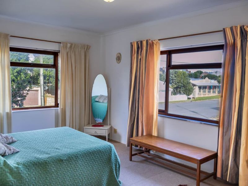 A well-lit bedroom featuring carpet flooring, timber window frames, and dual aspect windows providing natural light.