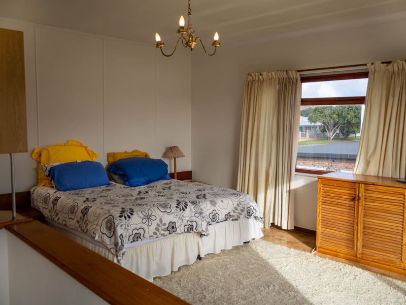 A bedroom featuring a built-in wooden cupboard, a classic chandelier, and a window with curtains.
