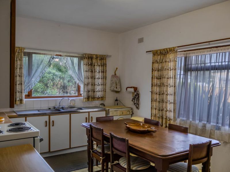 A functional kitchen featuring built-in cabinetry, a stainless steel sink, and an electric stove, offering potential for modernization and renovation.