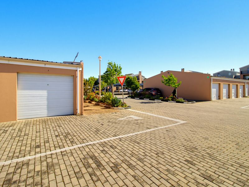 A view of the apartment complex parking area featuring multiple garage units and paved driveway access.
