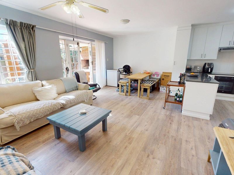 Open-plan living area featuring laminate flooring, a modern kitchen with granite countertops, built-in oven, and direct access to the outdoor patio area.