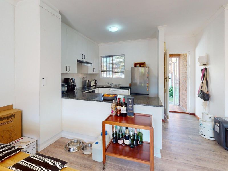 Compact kitchen featuring white cabinetry, granite countertops, and laminate flooring, with direct access to an exterior entrance.