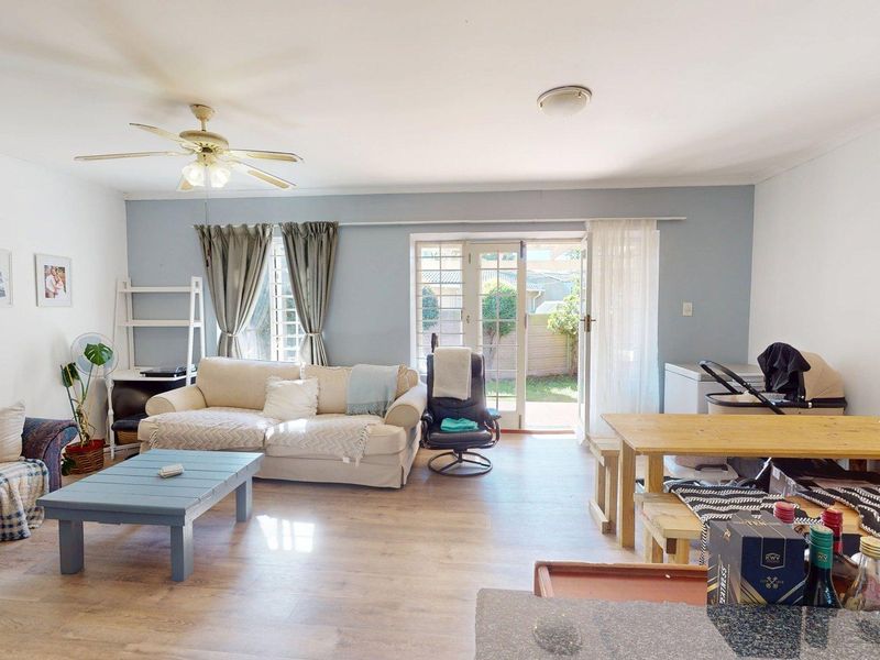 Spacious open-plan living area featuring laminate flooring, a ceiling fan, and direct access to the rear garden through glass french doors.