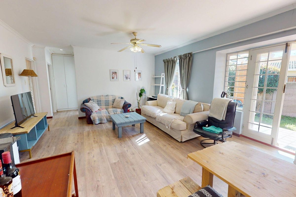 Spacious living room featuring laminate flooring, a ceiling fan, and direct access to the rear garden through glass french doors.