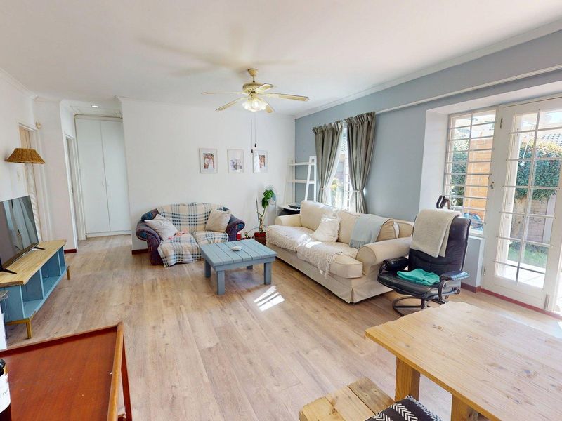 Spacious living room featuring laminate flooring, a ceiling fan, and direct access to the rear garden through glass french doors.