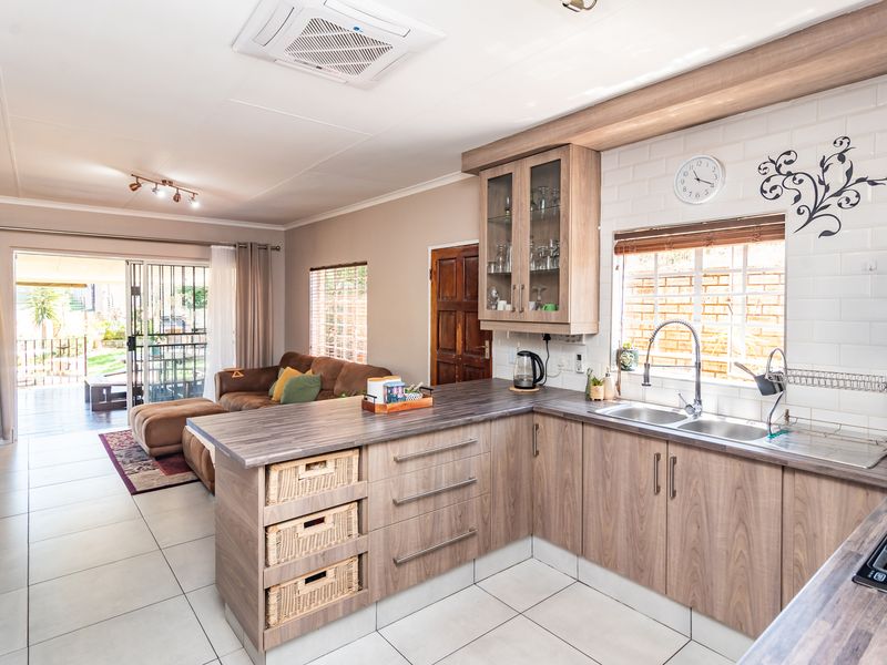 Open-plan living area featuring a modern kitchen with laminate cabinetry, subway tile backsplash, and direct access to an outdoor patio through sliding glass doors.