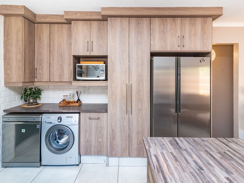 Modern kitchen featuring wood-grain cabinetry, laminate countertops, subway tile backsplash, and integrated appliance housing for a clean, functional workspace.