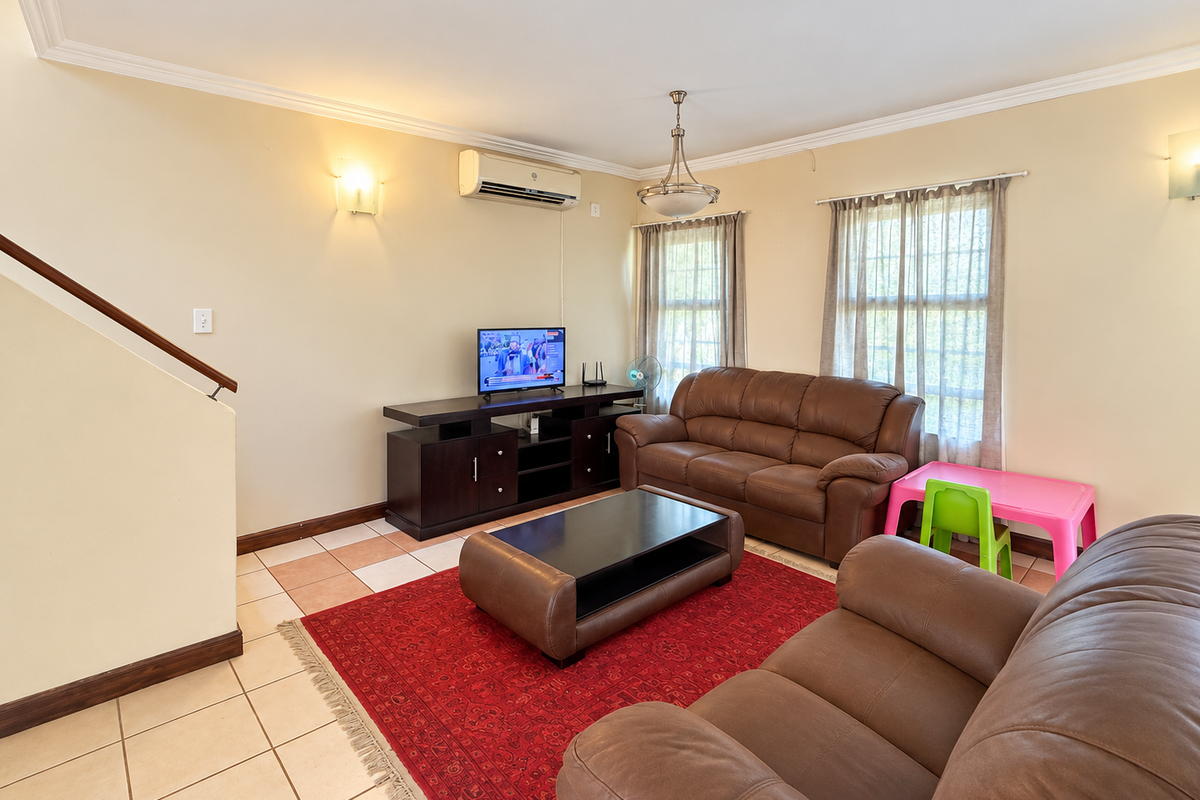 A comfortable living room featuring ceramic tile flooring, a split-system air conditioner, and a staircase with a wooden handrail.