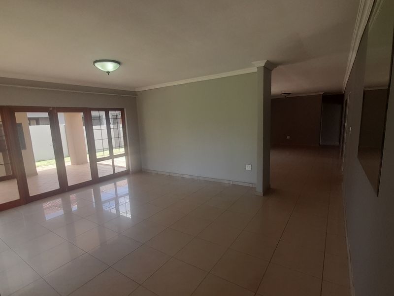 Spacious, empty living area featuring neutral tiled flooring, modern grey walls, and large sliding glass doors providing access to the outdoor patio.