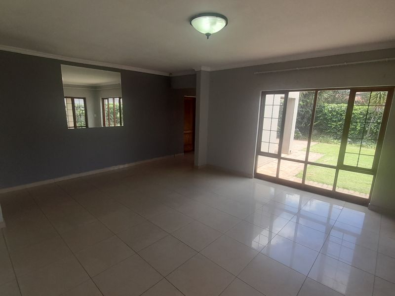 Spacious, empty living area featuring large sliding glass doors that provide natural light and direct access to the garden.