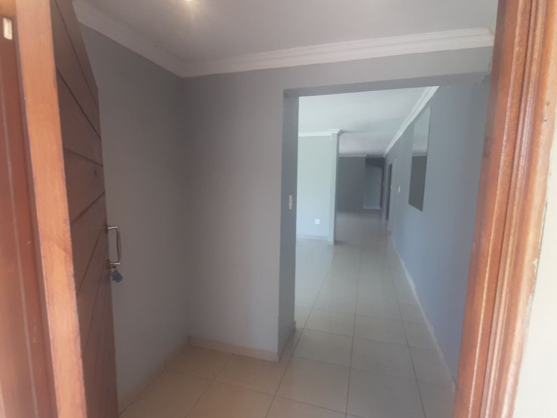An inviting entrance hall featuring neutral grey walls, tiled flooring, and recessed downlighting, leading into the main living area of the home.