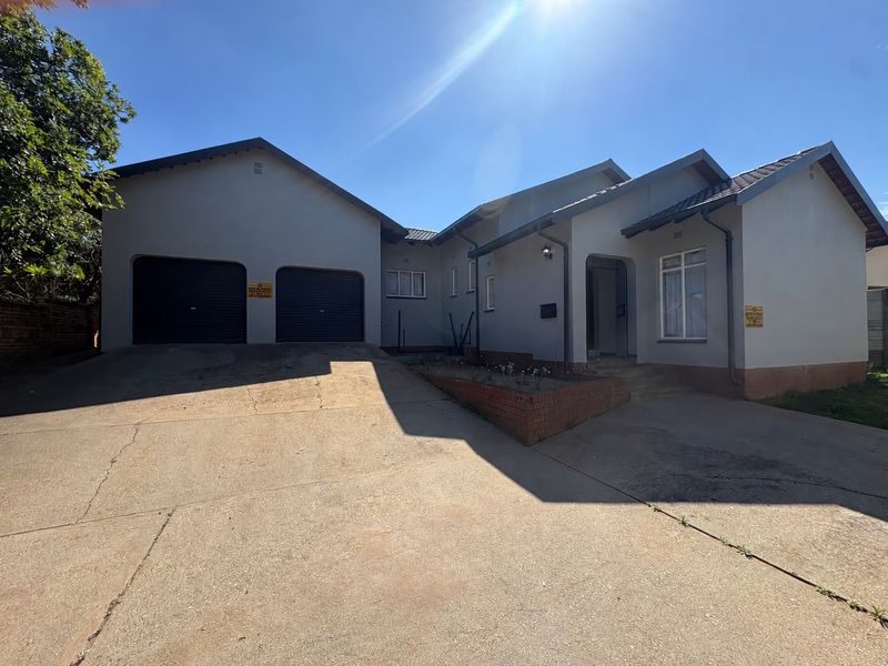 Front elevation of a single-story house featuring a double garage, concrete driveway, and a brick planter box at the entrance.