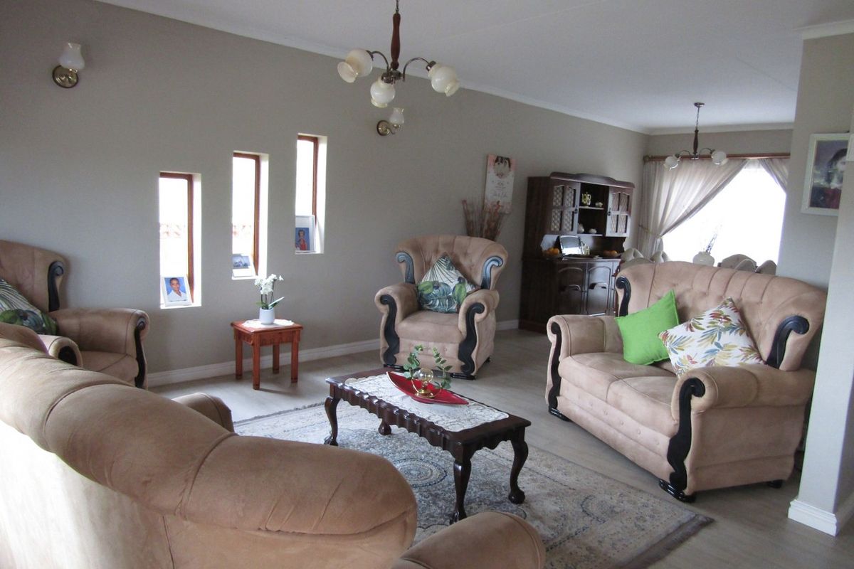Spacious living room featuring neutral wall tones, laminate flooring, and unique vertical window accents, providing a comfortable and well-lit area for relaxation.