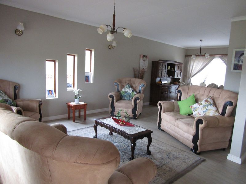 Spacious living room featuring neutral wall tones, laminate flooring, and unique vertical window accents, providing a comfortable and well-lit area for relaxation.