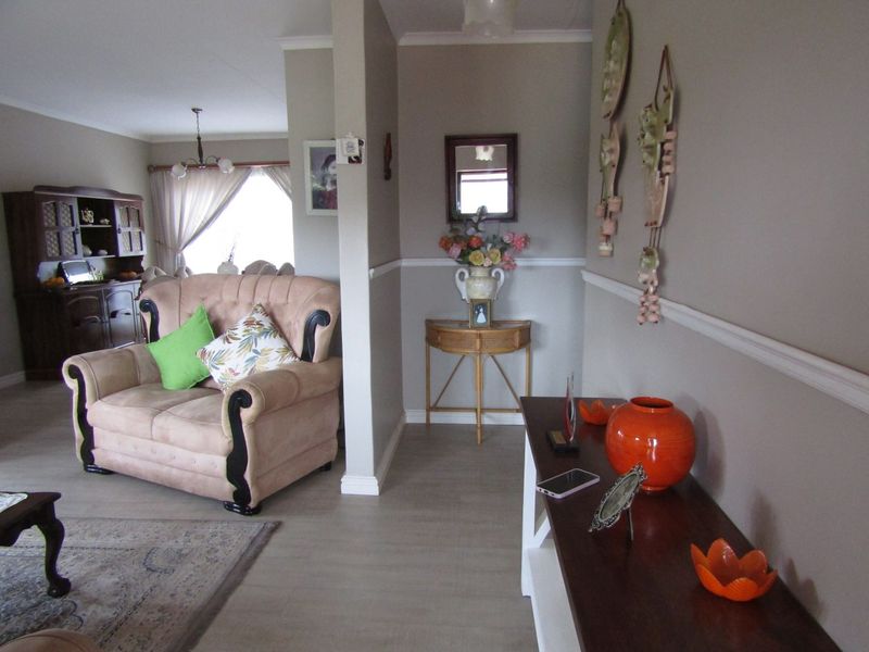 An open-plan living area featuring neutral wall tones, classic chair rail molding, and light-toned laminate flooring, creating a connected and functional living space.