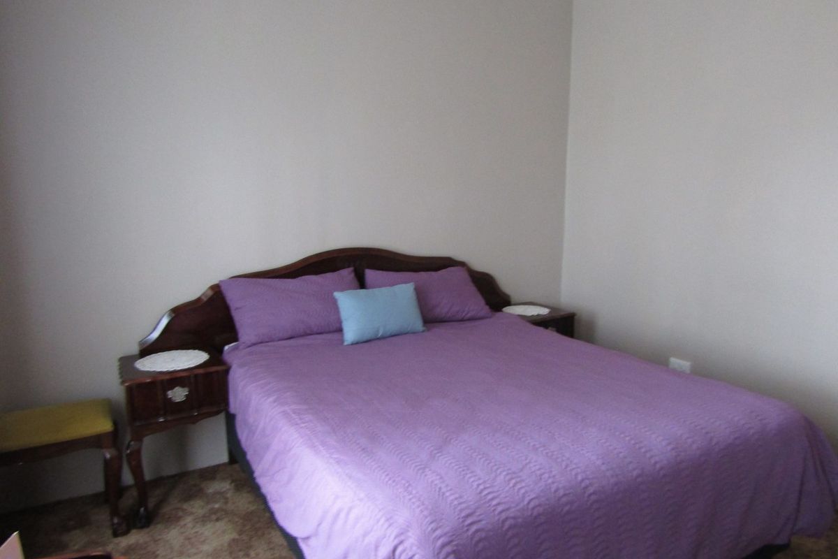 A standard bedroom featuring neutral wall paint, coving, and carpet flooring.