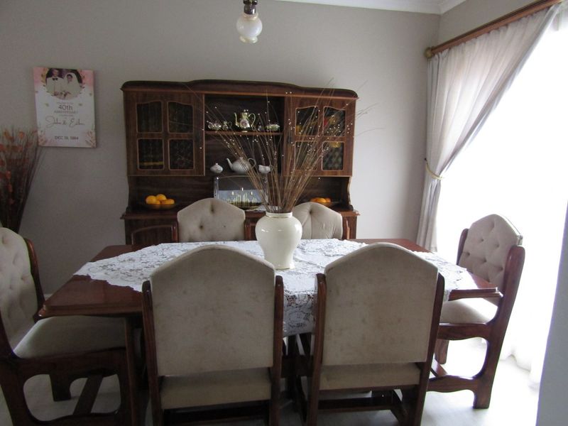 A traditional dining room featuring neutral wall tones, a ceiling light fixture, and window treatments.