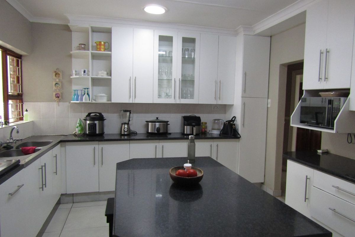 A well-maintained kitchen featuring white cabinetry, dark granite countertops, a central island, and integrated microwave, providing a clean and functional workspace.