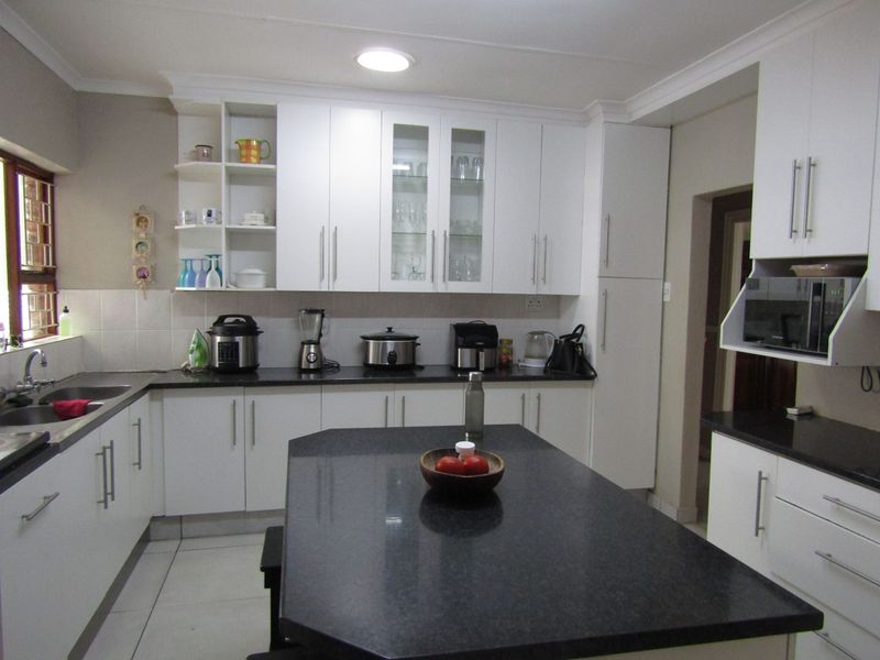 A well-maintained kitchen featuring white cabinetry, dark granite countertops, a central island, and integrated microwave, providing a clean and functional workspace.